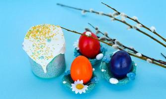 glücklich Ostern bunt Eier mit Kirsche Blüten und Kuchen legen auf Blau Hintergrund. Frühling Gruß Karte foto