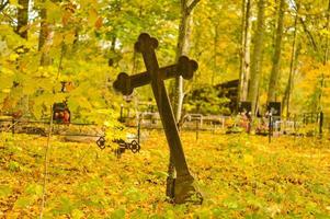 schwarz krumm metall Kreuz im beim das Friedhof im Herbst sonnig Wetter foto