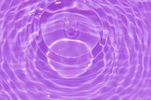 defocus verschwommene transparente lila gefärbte klare ruhige wasseroberflächenstruktur mit spritzer, blase. glänzender lila wasserkräuselungshintergrund. Wasseroberfläche im Schwimmbad. tropische lila wasserfarbe. foto