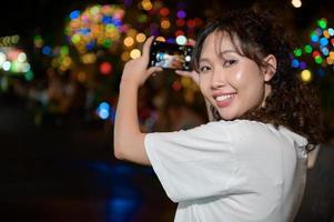 schön jung asiatisch Tourist Frau auf Ferien Besichtigung und erkunden beim khao san Straße beim Nacht im Bangkok Stadt, Thailand, Ferien und Reisen Konzept foto