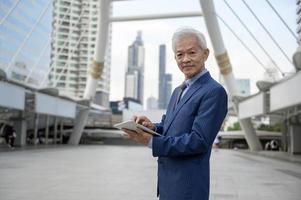 asiatisch Senior reifen Mitte alt Geschäftsmann mit Tablette im modern Stadt foto