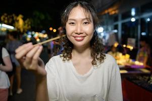 schön jung asiatisch Tourist Frau auf Ferien Besichtigung und erkunden beim khao san Straße beim Nacht im Bangkok Stadt, Thailand, Ferien und Reisen Konzept foto