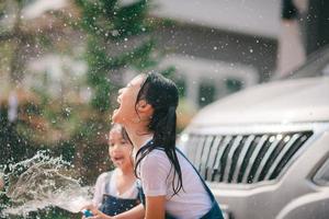 Geschwister asiatisch Mädchen waschen ihr Autos und haben Spaß spielen drinnen auf ein heiß Sommer- Tag. foto