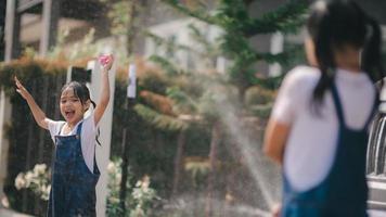 Geschwister asiatisch Mädchen waschen ihr Autos und haben Spaß spielen drinnen auf ein heiß Sommer- Tag. foto