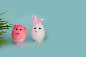 Ostern Urlaub, ein handgemacht Ei gemacht durch ein Kind im das bilden von ein Hase und Schwein gegen ein Blau Hintergrund. foto