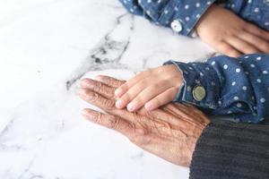 Kind hält die Hand einer älteren Person foto