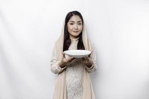 ein asiatisch Muslim Frau ist Fasten und hungrig und halten Utensilien Besteck während suchen beiseite Denken Über Was zu Essen foto