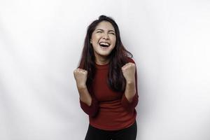 ein jung asiatisch Frau mit ein glücklich erfolgreich Ausdruck tragen rot oben isoliert durch Weiß Hintergrund foto