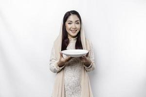 ein asiatisch Muslim Frau ist Fasten und hungrig und halten Utensilien Besteck während suchen beiseite Denken Über Was zu Essen foto