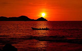 schön Ozean Sonnenuntergang Panorama mit Insel und Fischer Boot im Silhouette foto