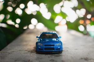 Konzept zum Natur Abenteuer. nach etwas bearbeitet, ein Foto von Blau Spielzeug Auto platziert in der Nähe von ein Baum.