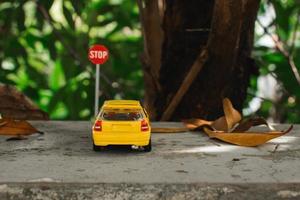 ein Foto von ein Gelb Spielzeug Auto trifft ein halt Zeichen, nach etwas bearbeitet.
