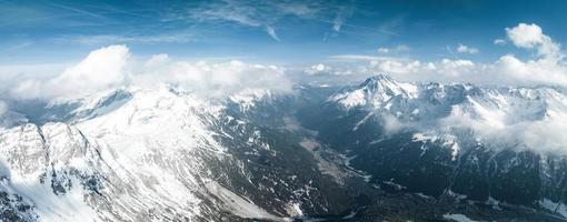 alpin Landschaft mit Spitzen bedeckt durch Schnee und Wolken. foto