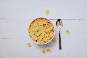 Cornflakes Frühstück im Schüssel und Löffel auf hölzern Hintergrund - - Müsli gesund Essen foto