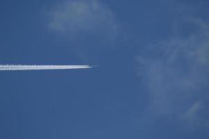 ein Flugzeug und Kondensstreifen am Himmel foto