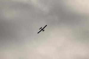 klein Flugzeug fliegend im das Himmel gegen dunkel Wolken foto