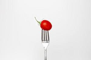 Foto von ein frisch Kirsche Tomate auf ein Gabel isoliert auf ein Weiß Hintergrund, Teil von ein Serie.