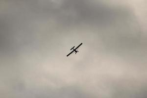 klein Flugzeug fliegend im das Himmel gegen dunkel Wolken foto