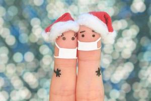 Finger Kunst von Paar im medizinisch Maske von covid-2019 feiert Weihnachten. Konzept von Menschen im Neu Jahr Hüte. getönt Bild. foto