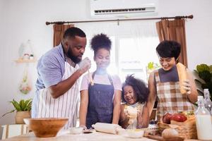 glücklich afrikanisch amerikanisch Familie genießen zusammen während bereiten das Mehl zum Herstellung Kekse beim Zuhause foto