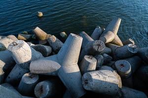 Tetrapoden-Wellenbrecher im Meerwasser. Wunderschöne Sonnenuntergangslandschaft mit Tetrapoden aus Beton zum Schutz von Küstenstrukturen vor Sturmwellen, Wettereinflüssen und Küstendrift foto