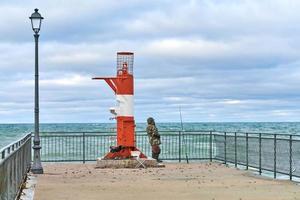 männlich Fischer im tarnen Angeln in der Nähe von Leuchtturm foto