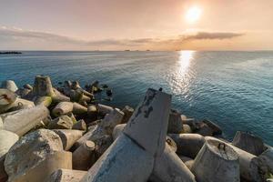 schöne sonnenuntergang seelandschaft. Wellenbrecher Tetrapoden an Land des Piers. Frachtschiffe am Horizont. Reiseträume und Motivation foto