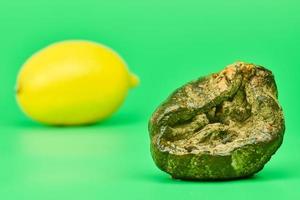 faule Zitrone und frische Zitrone vergleichen, grüner Hintergrund foto