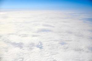 über den wolken draufsicht aus dem flugzeugfenster, dicke weißblaue wolken sehen aus wie weicher schaum foto