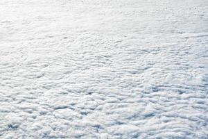 atemberaubender blick über die wolken aus dem flugzeugfenster, dicke weiße blaue wolken sehen aus wie weicher schaum foto