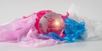 das Kristall Globus auf Plastik Tasche. Plastik Abfall überläuft das Welt. global Erwärmen und Klima Veränderung Konzept. foto