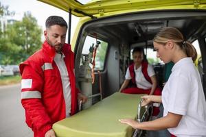 Sanitäter ziehen um aus Krankenwagen Bahre von Wagen. Sanitäter rollen das Krankenwagen Bahre foto