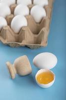 gebrochenes rohes Ei und Behälter der Eier auf einem blauen Hintergrund foto