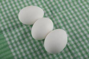 drei ungekochte Eier auf einer gestreiften Tischdecke foto