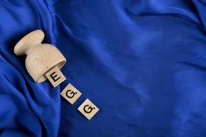 Holzbuchstaben, die das Wort Ei auf einem blauen Tuch buchstabieren foto