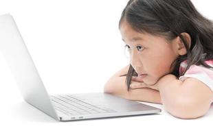 wenig Mädchen aussehen beim Monitor Laptop isoliert foto