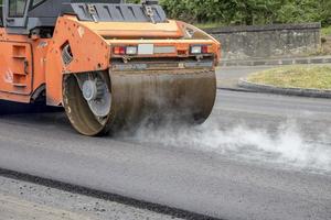 Trommel Walze beim das Konstruktion Grundstück, Arbeiten auf das Neu Straße mit Rauch foto