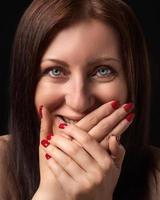 heiter Frau Lachen während Abdeckung Mund mit ihr Hände und Blick beim Kamera. Studio Porträt foto