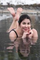 Plus Größe Modell- im schwarz Baden passen Lügen im geothermisch Mineral Wasser im Schwimmbad beim Balneotherapie Spa foto