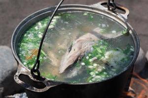 köstlich rot Lachs Fisch frische Suppe gekocht im groß Bowler auf draußen Lagerfeuer foto