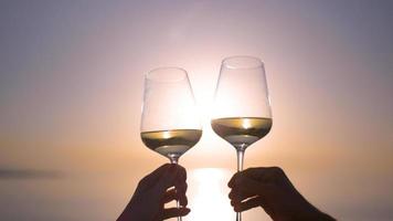 zwei Hände Herstellung ein Prost mit Wein Glas gegen funkelnd Meer und Himmel beim Sonnenuntergang foto