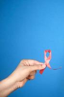 Hand hält rotes HIV-Band mit blauem Kopierraum foto