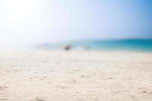 verschwommen Strand Hintergrund mit Sonnenstrahlen, Sommer- sandig leeren Strand foto