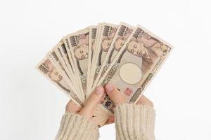 Frauenhand, die Banknotenstapel des japanischen Yen hält. Tausend Yen Geld. japanische bargeld-, steuer-, rezessionswirtschafts-, inflations-, investitions-, finanz- und einkaufszahlungskonzepte foto