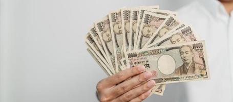 Hand des Mannes, die einen Stapel japanischer Yen-Banknoten hält. Tausend Yen Geld. japanische bargeld-, steuer-, rezessionswirtschafts-, inflations-, investitions-, finanz- und einkaufszahlungskonzepte foto