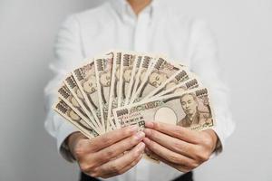 Hand des Mannes, die einen Stapel japanischer Yen-Banknoten hält. Tausend Yen Geld. japanische bargeld-, steuer-, rezessionswirtschafts-, inflations-, investitions-, finanz- und einkaufszahlungskonzepte foto