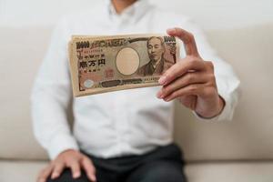 Hand des Mannes, die einen Stapel japanischer Yen-Banknoten hält. Tausend Yen Geld. japanische bargeld-, steuer-, rezessionswirtschafts-, inflations-, investitions-, finanz- und einkaufszahlungskonzepte foto