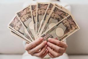 Frauenhand, die Banknotenstapel des japanischen Yen hält. Tausend Yen Geld. japanische bargeld-, steuer-, rezessionswirtschafts-, inflations-, investitions-, finanz- und einkaufszahlungskonzepte foto