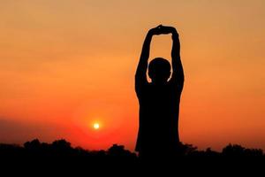 Silhouette von männlich meditieren und Yoga üben mit Übung beim Sonnenaufgang im Öffentlichkeit Park Morgen foto