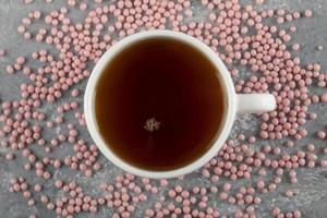 eine weiße Tasse heißen Tee mit rosa Streuseln foto